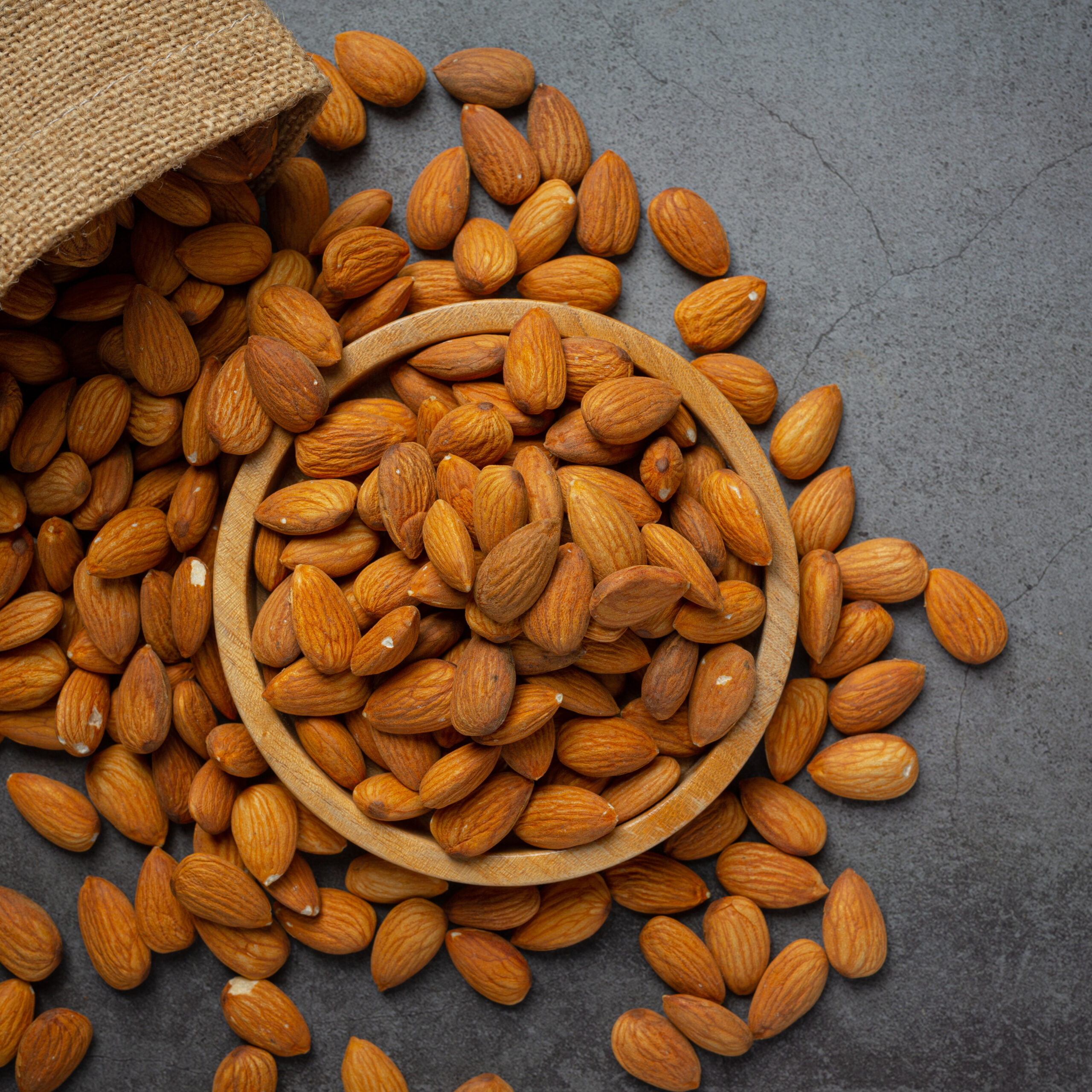 Almonds in bowl on dark background