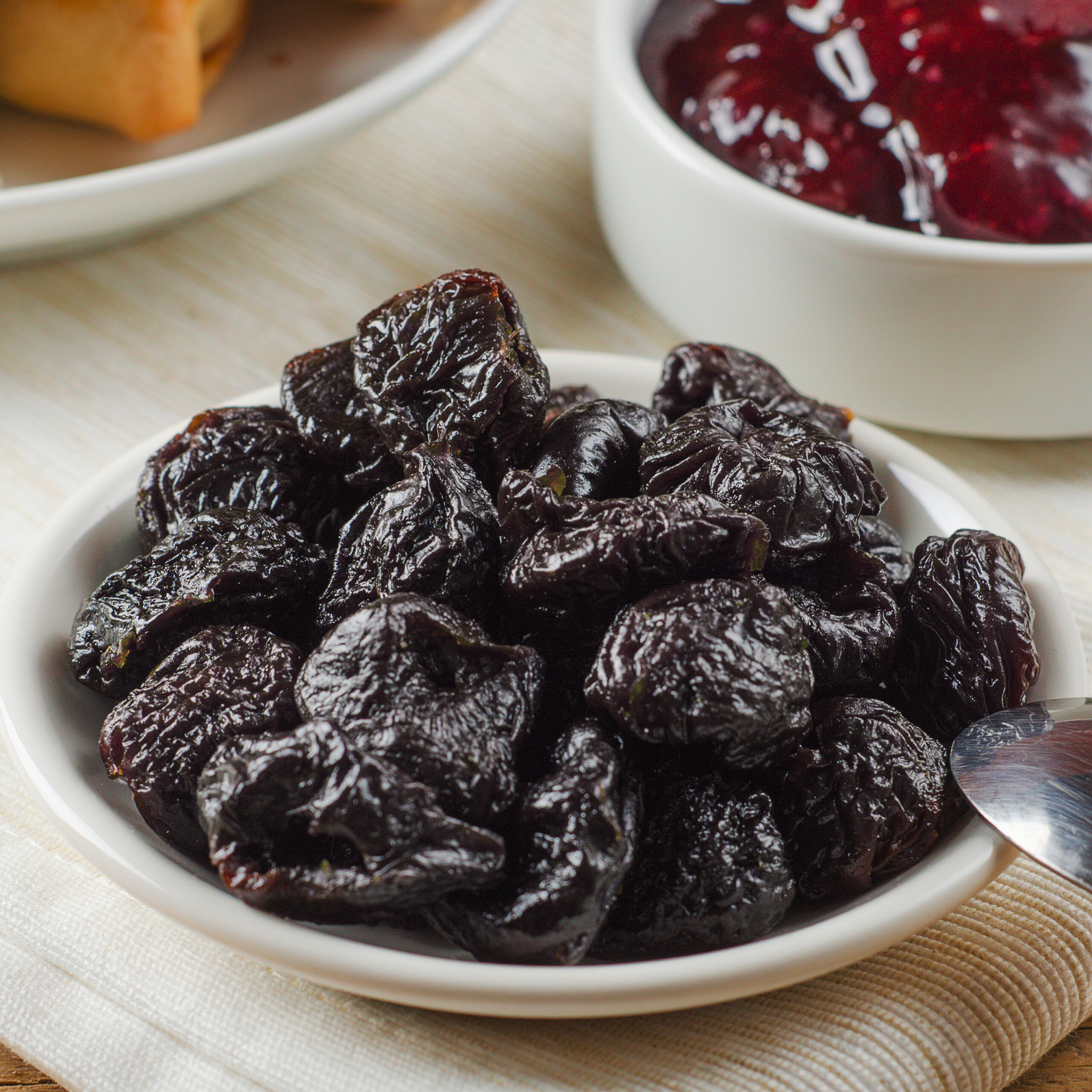 Prunes on small plate with jam from the plums on wooden table. Dried Plums. Healthy and vegetarian food.