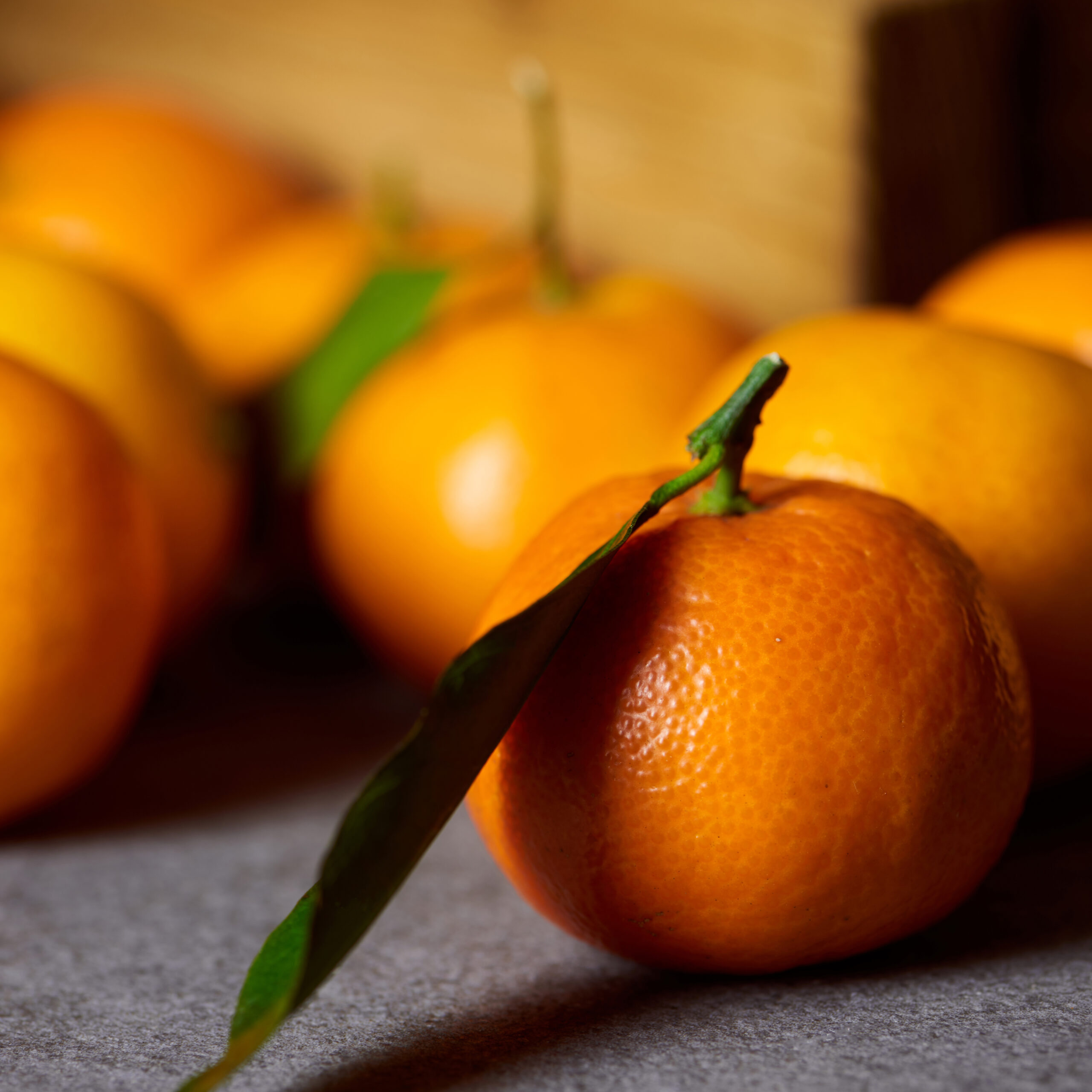 selective focus of orange clementine near tangerines with green